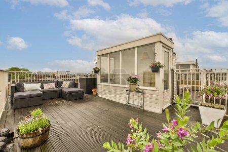 Photo for A roof deck with flowers and potted plants in the fore - image was taken from an outside viewing point - Royalty Free Image