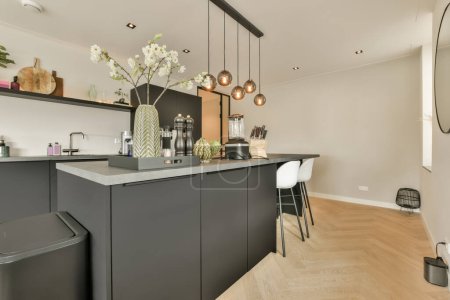 Téléchargez les photos : Une cuisine moderne avec armoires noires et comptoirs blancs au centre de la pièce est un grand miroir sur le mur - en image libre de droit