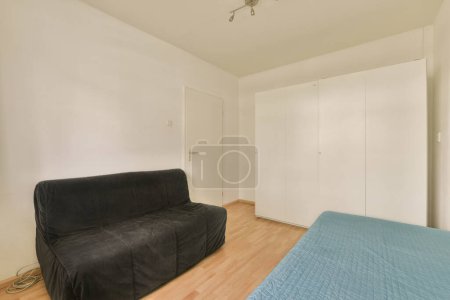 Photo for A bedroom with a black couch and white closets in the room is very clean, but its not too - Royalty Free Image