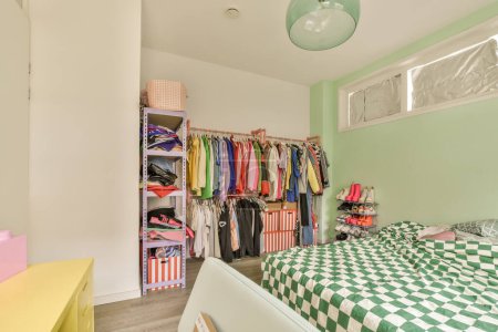 Photo for A green and white checkereded bed in a room with two closets on either sides, one is open to the other - Royalty Free Image