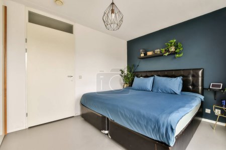 Foto de Un dormitorio con ropa de cama azul y cabeceros negros en la pared por encima de la cama es una puerta blanca - Imagen libre de derechos