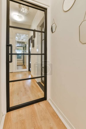 Foto de Una habitación vacía con suelos de madera y puertas de vidrio que conducen a la sala de estar hay espejos colgando de la pared - Imagen libre de derechos