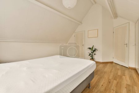 Photo for A bedroom with white walls and wood flooring the room has a bed, two closets on either sides - Royalty Free Image
