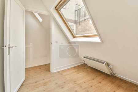 Photo for An attic room with wood flooring and skylights on the side of the window above it is a white rad - Royalty Free Image