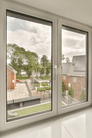 Photo for An empty room with windows that look out onto the street, and houses are visible in the window panes - Royalty Free Image