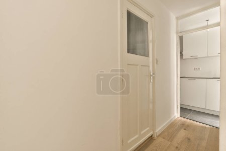 Téléchargez les photos : Une pièce vide avec des murs blancs et du parquet sur le côté droit de la pièce, il y a une porte menant à une autre - en image libre de droit