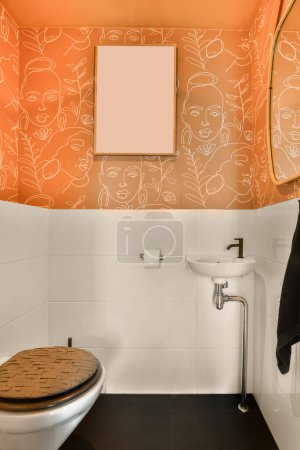 Foto de Un cuarto de baño con una pared naranja y azulejos blancos en las paredes, junto con un aseo delante de un espejo - Imagen libre de derechos