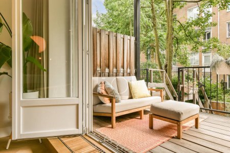 una zona exterior con un sofá y una silla en la cubierta con vistas a los árboles en el patio detrás de ella