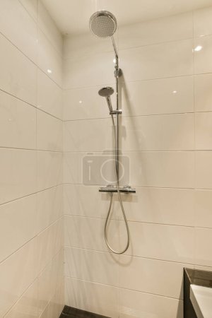 Téléchargez les photos : Une salle de bain moderne avec des murs de tuiles blanches et des carreaux noirs sur le sol, il y a une pomme de douche dans le coin - en image libre de droit