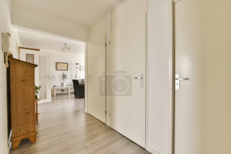 Photo for An empty room with white walls and wood flooring in the middle part of the room, there is a door leading to another - Royalty Free Image