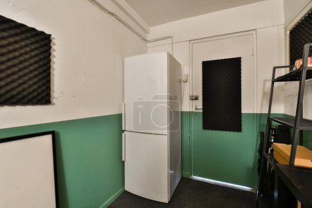 Photo for A green and white room with two refrigerators, one on the wall and another on the floor in the corner - Royalty Free Image