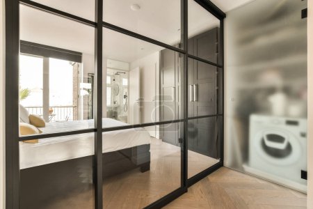 Foto de Un dormitorio con un gran espejo en la pared, y una cama blanca en la habitación se refleja en la puerta de cristal - Imagen libre de derechos