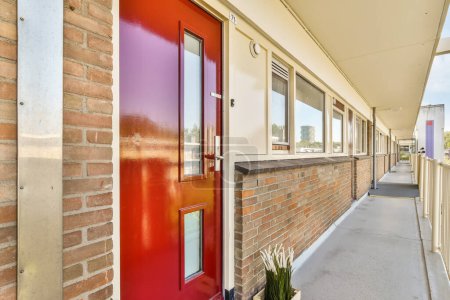 Téléchargez les photos : Une porte rouge sur le côté d'un bâtiment en brique peint en orange vif et violet avec des garnitures blanches - en image libre de droit