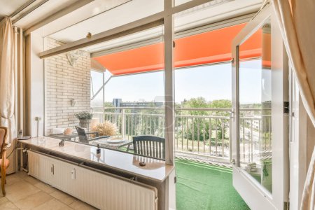 Téléchargez les photos : Un salon avec un auvent orange sur la fenêtre sie et herbe verte dans la vue est à l'extérieur - en image libre de droit