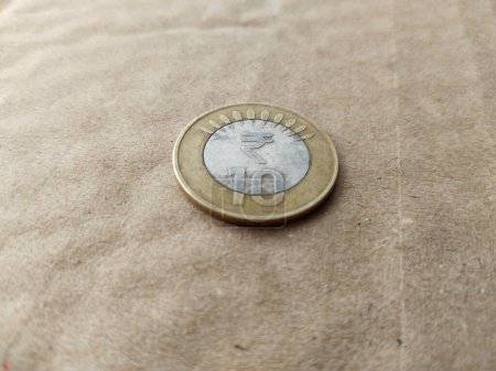Foto de Moneda india moneda de diez rupias aislada en el fondo wheatish. - Imagen libre de derechos