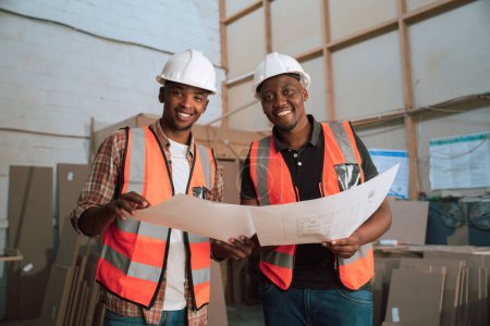 Photo for Young African building contractors and business partners discussing designs - Royalty Free Image
