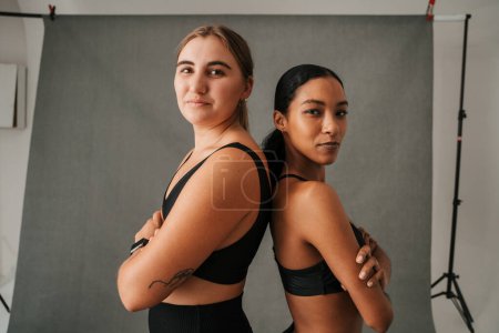Foto de Dos amigas enfocadas espalda con espalda antes de la clase de gimnasia allí ropa deportiva. Foto de alta calidad - Imagen libre de derechos