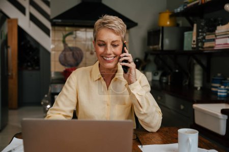 Photo for Senior woman working from home talking on mobile device. High quality photo - Royalty Free Image
