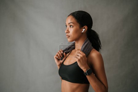 Photo for Focused Multiethnic female with toned body towel over shoulder ear pods in and ready for gym. High quality photo - Royalty Free Image