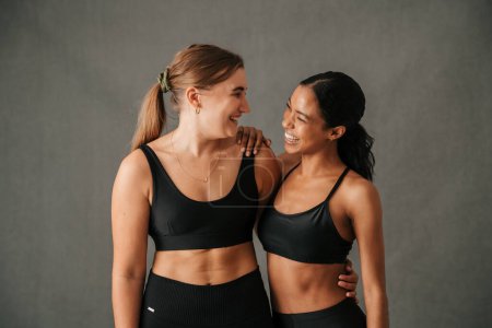 Photo for Close up of two girls arm in arm smiling and laughing showing there toned bodies after great work out. High quality photo - Royalty Free Image