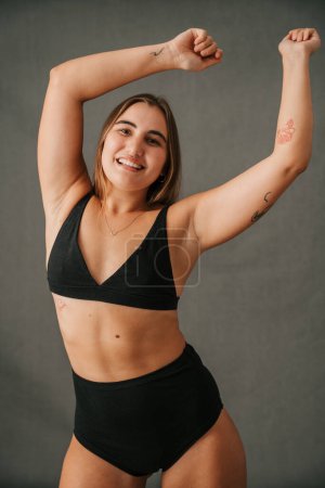 Foto de Bailando sonriente hembra caucásica mostrando su tatuaje en su brazo en su ropa activa en el estudio. Foto de alta calidad - Imagen libre de derechos
