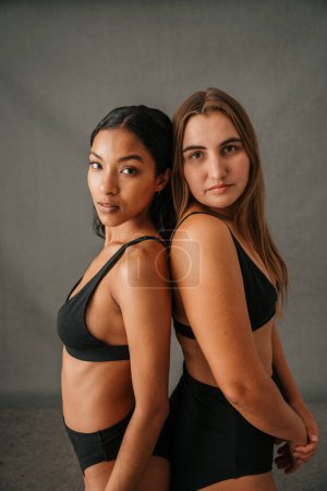 Photo for Portrait girlfriends standing back to back in there black underwear in the studio. High quality photo - Royalty Free Image