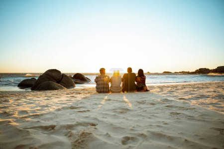 Photo for A beach with four people sitting together at sunrise. High quality photo - Royalty Free Image