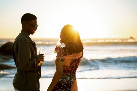 Téléchargez les photos : Un couple prenant un verre sur la plage au coucher du soleil. Photo de haute qualité - en image libre de droit