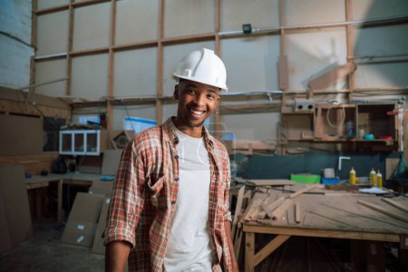 Photo for Happy African American male with hardhat stands in carpentry factory. High quality photo - Royalty Free Image