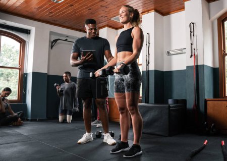 Photo for A man and a woman in sportswear are chatting by the gym window. The man points to his thigh while the woman touches her waist and chest - Royalty Free Image
