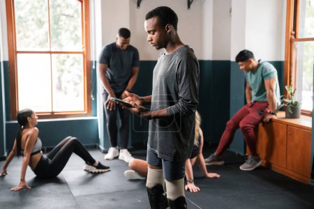 Photo for A group of people are working out in a gym, exercising their arms, legs, muscles, and thighs. They are sharing the space in the building with large windows and sturdy flooring - Royalty Free Image