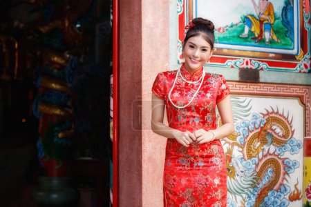 Mujer china en un vestido rojo cheongsam rendir homenaje a dios chino en el santuario. Concepto para celebrar el Año Nuevo Chino.
