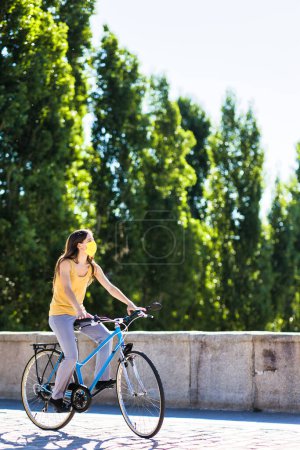 Foto de Bicicleta en bicicleta en la calle urbana con covid19 máscara de protección. transporte movilidad sostenible. virus epidemia de salud médica. - Imagen libre de derechos