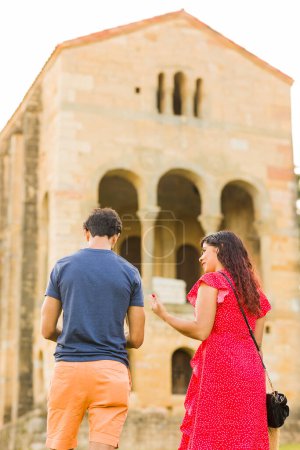 Téléchargez les photos : Homme indien adulte moyen et femme latine devant l'église historique préromane médiévale de l'Unesco. monument européen. deux personnes ensemble. - en image libre de droit