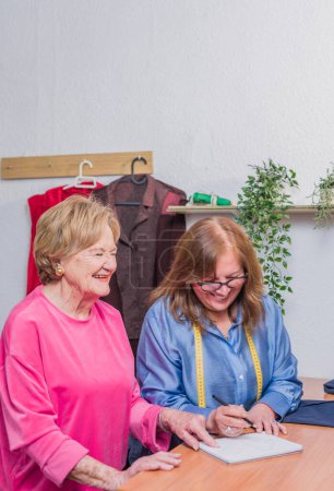 Foto de Latin chilean Needlewoman haciendo ropa en su taller. ocupación de moda lenta de una pequeña empresa latina con un pensionista jubilado de edad avanzada. moda sostenible - Imagen libre de derechos