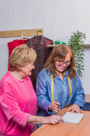 Téléchargez les photos : Mesure entrepreneur de travail avec ruban à mesurer pour réutiliser le tissu pour une mode écologique durable. bonheur hispanique positif - en image libre de droit