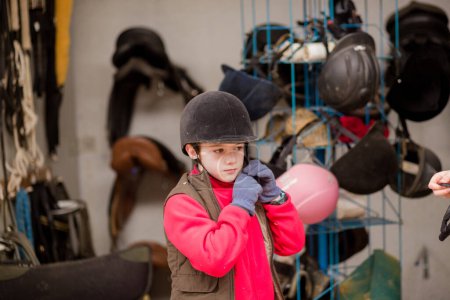 Photo for Equine recreation equipment for rider protection. Horseback jockey equestrian helmet uniform with. Kid wearing during training in the paddock. - Royalty Free Image