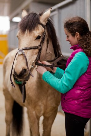 Photo for Teenage girl enjoy rider adjusting saddle and equipment for horse riding dressage. Horsewoman childhood. Equestrian animal bridle - Royalty Free Image