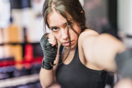 Téléchargez les photos : Légitime défense, MMA et Kickboxing ring. Sportswoman avec détermination et confiant de travailler et de l'exercice de poinçonnage avec la boxe cardio - en image libre de droit