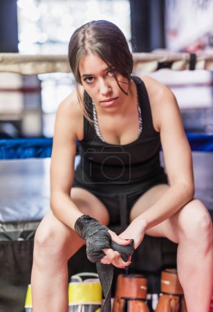 Photo for Healthy lifestyle determination and motivation for martial arts self-defense MMA or Kickboxing. Woman putting on protective equipment - Royalty Free Image