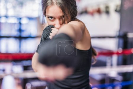 Photo for Self-defense, MMA and Kickboxing ring. Sportswoman with determination and confident working out and exercise punching with cardio boxing - Royalty Free Image