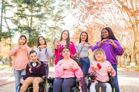 Photo for Women with cerebral palsy outdoors celebrating 8th march with their feminist friends, togetherness with sorority for inclusion and female rights - Royalty Free Image