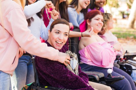 Photo for Women with cerebral palsy outdoors celebrating 8th march with their feminist friends, togetherness with sorority for inclusion and female rights - Royalty Free Image