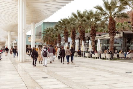 Photo for Malaga, Spain- 26-01-2024: Busy promenade in Malaga with people walking and outdoor cafes under a modern canopy, ideal for travel and lifestyle themes. Winter in Spain. Muelle Uno Street - Royalty Free Image