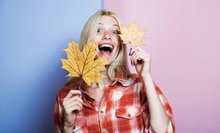 Moda otoño mujer feliz con hojas de arce amarillo. Sonriente chica rubia en camisa a cuadros