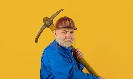 Photo for Construction worker in uniform with pickaxe. Miner man with pickaxe. Mining industry. Male laborer with building tools. Bearded builder in hardhat with pickax. Workman in safety helmet with pick ax - Royalty Free Image