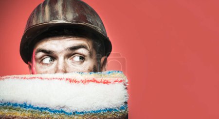 Photo for Male painter in hard hat with paint roller. Closeup portrait of painter, contractor or decorator in protective helmet with paintroller. Room painting job. To make repairs. Copy space for advertising - Royalty Free Image