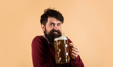 Beer time. Celebration Oktoberfest festival. Happy bearded man drinking beer in pub or bar. Handsome male with foamy beer mug. Beer degustation. Lager or dark ale. Alcohol, drinks and holiday concept