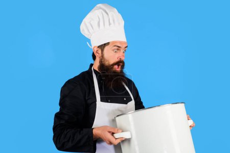 Photo for Cooking food. Surprised bearded man in chef hat and uniform with casserole or saucepan. Male chef cook in apron with big pot or pan. Cookware, dinnerware, kitchenware and kitchen utensils concept - Royalty Free Image