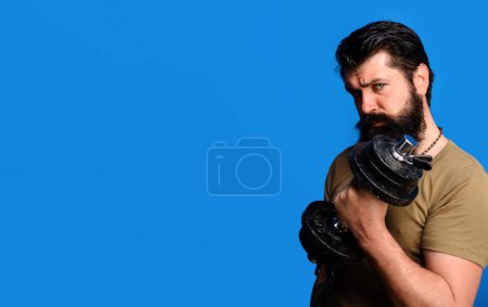 Photo for Sport lifestyle, weightlifting and bodybuilding concept. Handsome man lifting dumbbell at gym. Athletic bearded male model with dumbbell for weight training in sport club. Copy space for advertising - Royalty Free Image